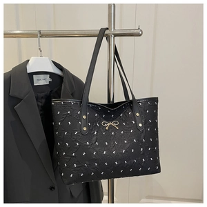Détail du sac cabas matelassé noir avec nœuds blancs et ornements dorés chic