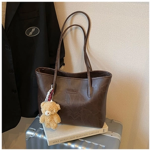 Detailed macro view of dark brown tote bag with fashion lettering and cute bear charm