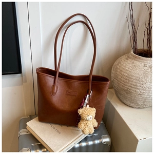 Detail of vintage brown tote bag with FASHION logo and decorative bear keychain charm
