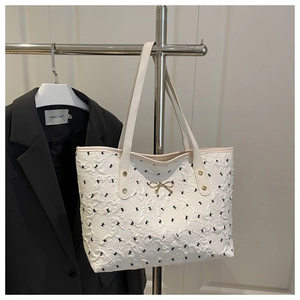 Détail du sac cabas blanc avec texture gaufrée, motifs floraux et boucle de nœud dorée
