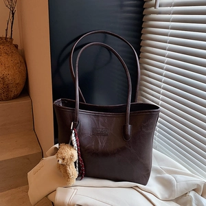 Classic dark brown leather tote bag with fashion embossing and cute bear charm accessory
