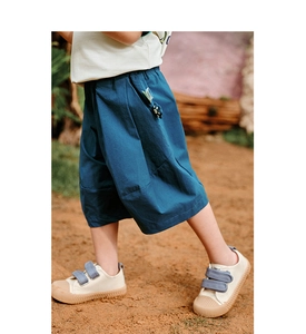 Close-up of peacock blue loose cotton trousers with detailed stitching and canvas shoes