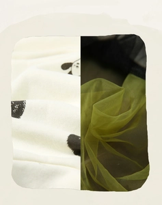 Detail von weichem weißem Strickstoff mit schwarzen Punkten und limettengrüner Netzlage