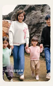 Family in matching round neck sweaters with heart embroidery during outdoor city walk