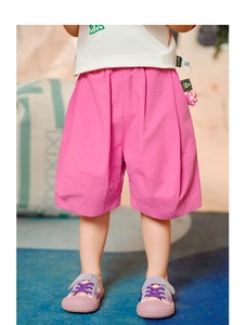Detail of bright pink kids shorts featuring elastic waistband and brand label