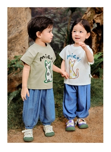 Kids casual summer outfit featuring a cartoon cat t-shirt and loose denim pants in a garden