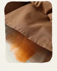 Dettaglio del tessuto in cotone marrone con strati di tulle arancione a rete