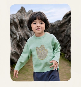 Detail van mintgroene gebreide trui met berenpatch en geribbelde boorden voor kids