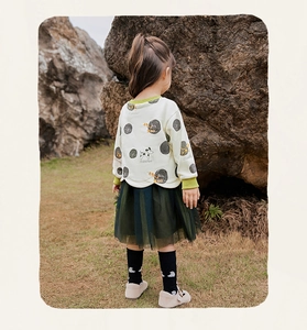 Detail eines Mädchen-Herbstoutfits mit Polka-Dot-Sweatshirt und grünem Tüllrock