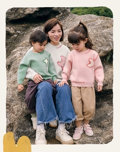 Detail view of knitted sweaters with decorative contrast stitching and soft cotton texture