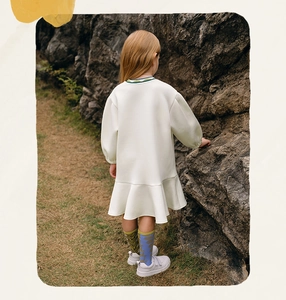 Rear view of cream-colored long sleeve dress with frilled hem for girls in outdoor setting