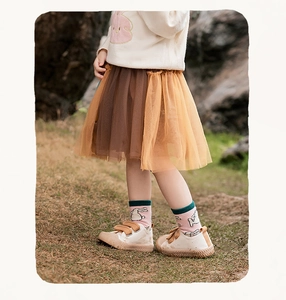 Dettaglio gonna tutu in tulle irregolare per bambina con strati marroni e giallo zenzero