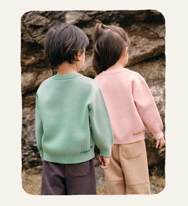 Detail of loose-fit knit sweaters with colorful hand-stitched embroidery on the hemline