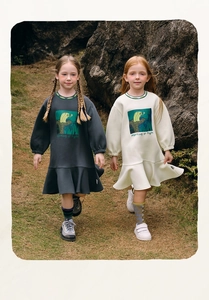 Detailed close-up of girls autumn sweatshirt dress with ruffled hem and artistic print