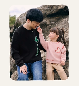Matching parent-child knitted sweaters in black and pink with artisanal embroidery details
