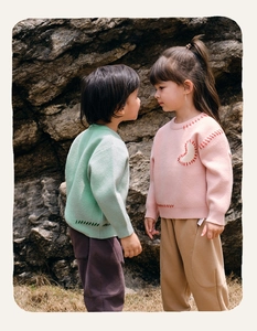 Close-up of mint green and pink knit sweaters with heart patterns for children