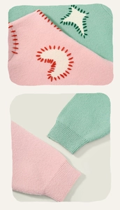Detail of ribbed cuffs and moon star embroidery on soft knit pink and green sweaters