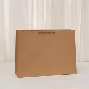 Detail of a brown kraft paper shopping bag with twisted handles on a white surface