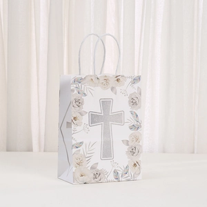 Detailed view of a white religious gift bag with silver glitter cross and floral patterns