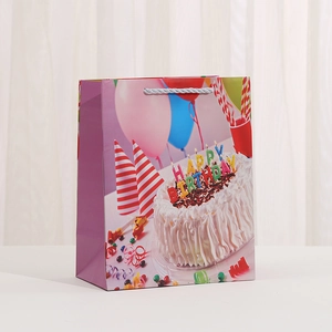 Detail of white card gift bag featuring a birthday cake, balloons and silver handles