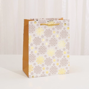Vertical white card Christmas gift bag with golden snowflake patterns and woven handles