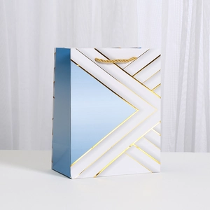 Minimalist white and blue gift bag with gold geometric foil lines and woven handles
