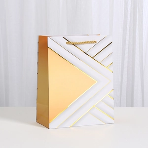 Detail of gold geometric triangles and woven rope handle on a white gift paper bag