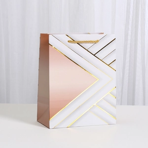 Elegant white and rose gold geometric pattern paper gift bag with gold braided handles