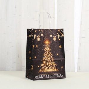 Detail van een zwarte kerstcadeautas met een gouden boom en witte papieren handvatten