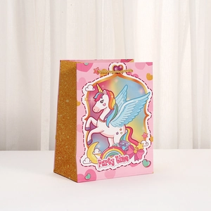 Detail of pink paper gift bag featuring unicorn illustration and gold glitter side accents