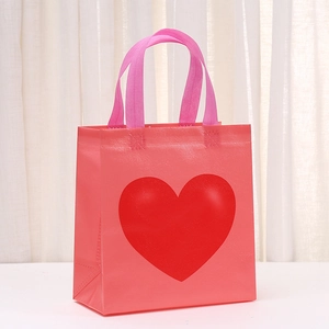 Pink waterproof non-woven gift bag with a large red heart print and ribbon handles