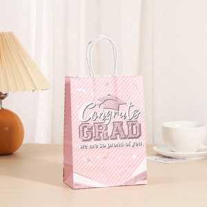 Detail view of a pink graduation gift bag with 'Congrats GRAD' text and white handle