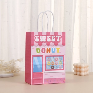 Detailed view of a pink Sweet Donut paper gift bag with white rope handles on a table