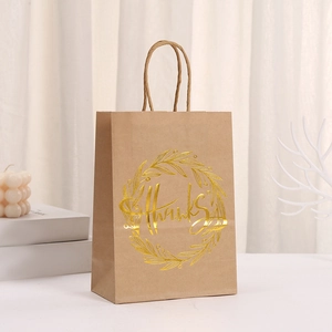 Close-up of brown Kraft paper bag featuring gold foil 'Thanks' lettering and twisted handle