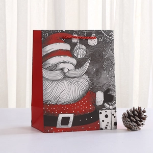 Christmas gift bag with Santa Claus illustration and red rope handles on white background