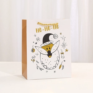 Detailed close-up of Christmas paper gift bag with gold foil Ho-Ho-Ho and gold rope handles