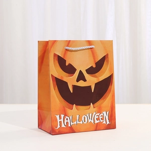 Sac cadeau Halloween orange avec motif citrouille et poignées blanches sur table blanche