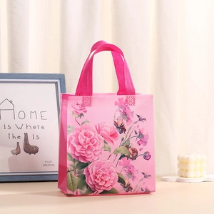 Detalle de bolsa de regalo floral rosa en tela no tejida con asas resistentes