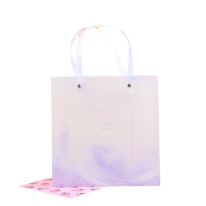 Bolsa de regalo degradada rosa y morada con motivos de estrellas y asas tejidas blancas
