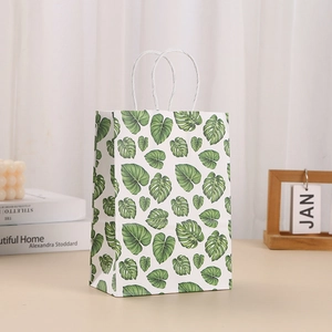 Detail of white kraft paper gift bag with green monstera leaf print and twisted handles