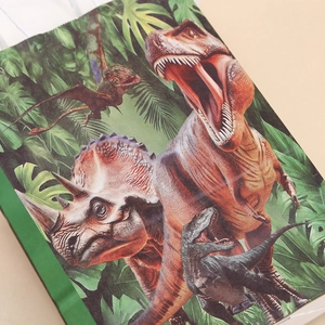 Green dinosaur themed paper gift bag with colorful prehistoric creature prints and handles