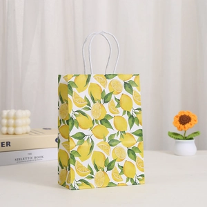 Lemon print paper gift bag with white handles shown in a cozy indoor lifestyle setting