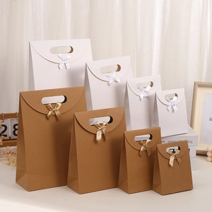Various sizes of kraft paper gift bags with ribbon bows and semi-circular handles