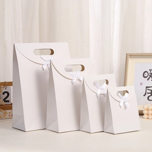 Set of four white kraft paper gift bags with flip lids and decorative silk bows