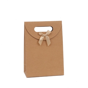Brown kraft paper gift bag with a champagne silk bow and die-cut handle on white background