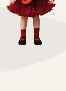 Close-up of a festive red layered tutu skirt, polka dot socks, and black Mary Jane shoes