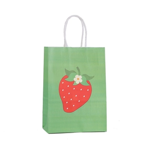 Detalle de bolsa de papel verde con estampado de fresa y asas de cuerda blanca
