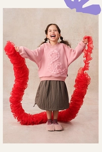 Detail of pink fleece sweatshirt with tulle ruffle design and brown pleated skirt