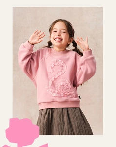 Detail of girls' light pink sweatshirt featuring 3D ruffled trim and warm fleece fabric