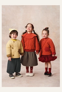 Three children wearing winter quilted jackets with traditional Chinese knots and skirts